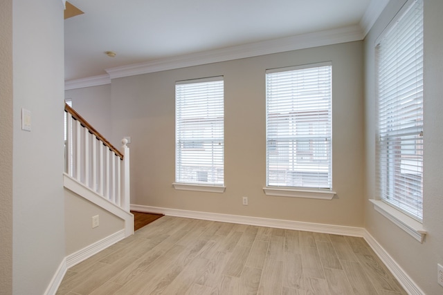 unfurnished room featuring ornamental molding and light wood-type flooring