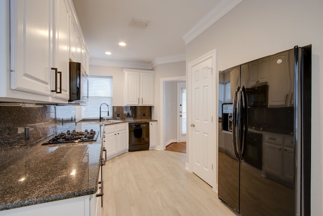 kitchen featuring crown molding, white cabinets, dark stone counters, decorative backsplash, and black appliances