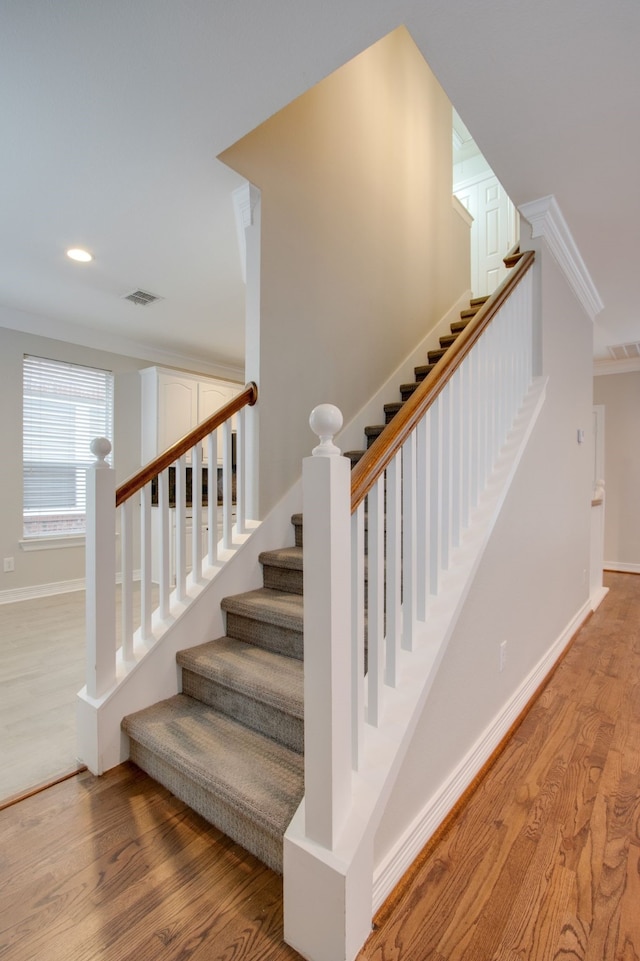 staircase featuring hardwood / wood-style flooring and ornamental molding