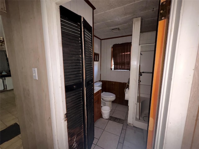 bathroom featuring tile patterned flooring, wooden walls, and toilet