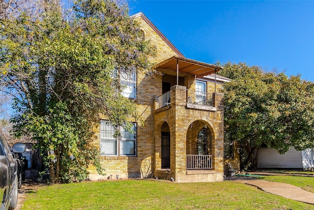 view of front facade featuring a balcony and a front yard