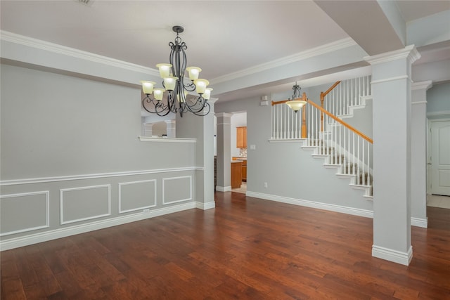 unfurnished dining area with crown molding, dark hardwood / wood-style floors, a chandelier, and ornate columns