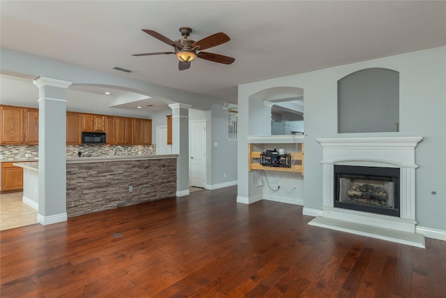 unfurnished living room featuring dark hardwood / wood-style flooring, decorative columns, and ceiling fan