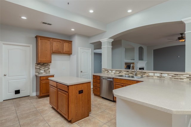 kitchen featuring sink, ceiling fan, dishwasher, a kitchen island, and ornate columns