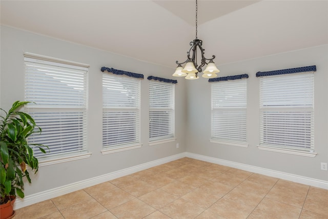 spare room with lofted ceiling, light tile patterned floors, and an inviting chandelier