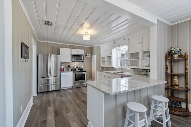 kitchen featuring a breakfast bar, white cabinetry, sink, kitchen peninsula, and stainless steel appliances