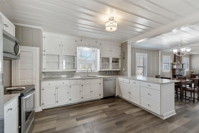 kitchen with appliances with stainless steel finishes, a wealth of natural light, kitchen peninsula, and white cabinets