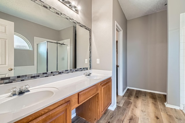 bathroom with wood-type flooring, a shower with shower door, a textured ceiling, and vanity