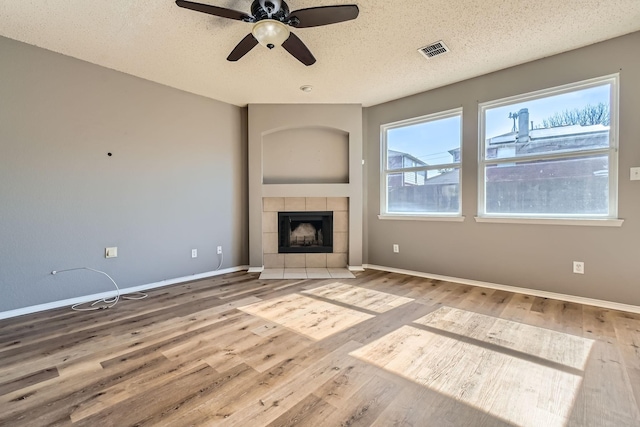 unfurnished living room with hardwood / wood-style floors, a fireplace, a textured ceiling, and ceiling fan