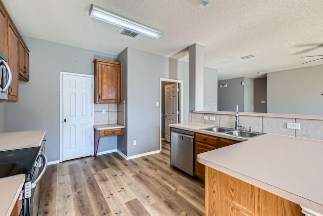 kitchen with wood-type flooring, sink, decorative backsplash, stainless steel appliances, and a textured ceiling