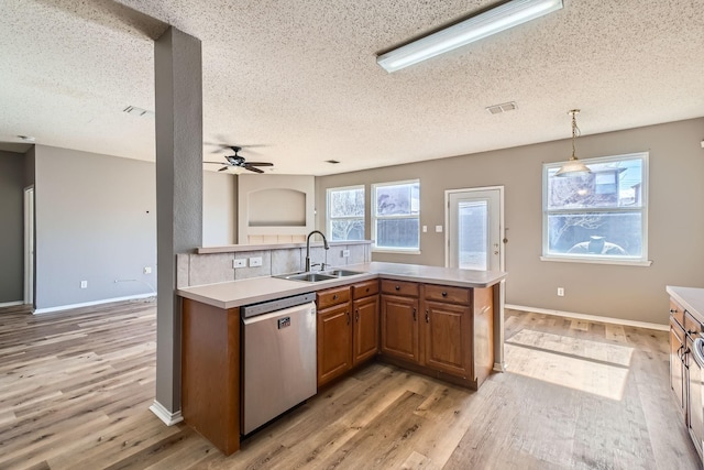 kitchen featuring pendant lighting, dishwasher, sink, and light wood-type flooring