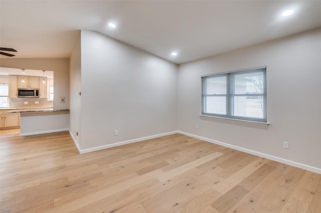 spare room featuring lofted ceiling, ceiling fan, and light hardwood / wood-style flooring