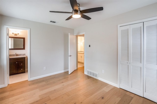 unfurnished bedroom with ceiling fan, a closet, ensuite bathroom, and light hardwood / wood-style flooring