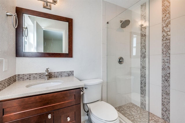 bathroom with vanity, tiled shower, and toilet