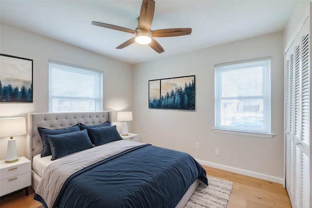 bedroom featuring multiple windows, light hardwood / wood-style floors, a closet, and ceiling fan