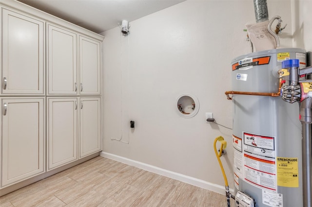 laundry area with cabinets, gas water heater, hookup for an electric dryer, and light hardwood / wood-style floors