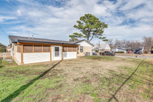 rear view of property featuring cooling unit and a lawn