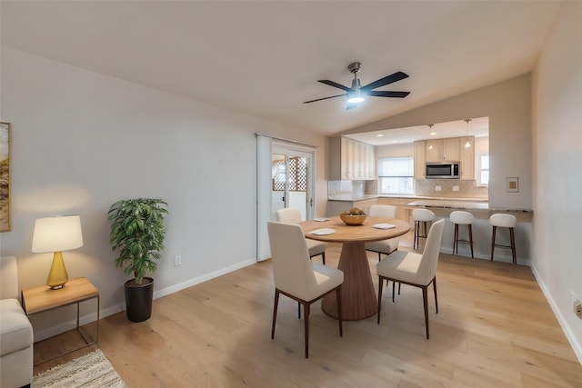 dining space with vaulted ceiling, light hardwood / wood-style floors, and ceiling fan