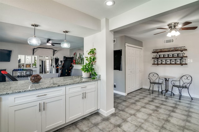 kitchen featuring white cabinetry, kitchen peninsula, light stone counters, and pendant lighting