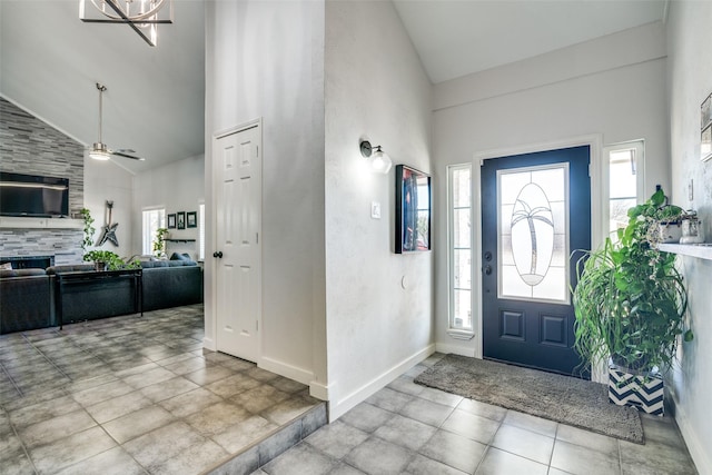 tiled foyer entrance featuring ceiling fan, a fireplace, and high vaulted ceiling