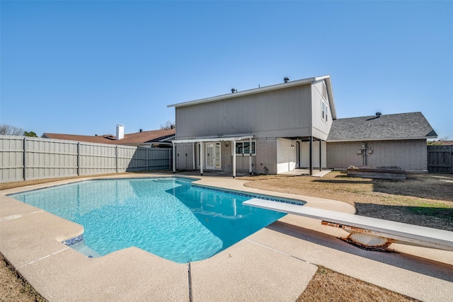 view of pool with a diving board and a patio area