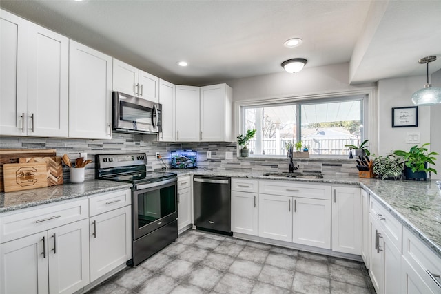 kitchen with stainless steel appliances, sink, white cabinets, and decorative light fixtures