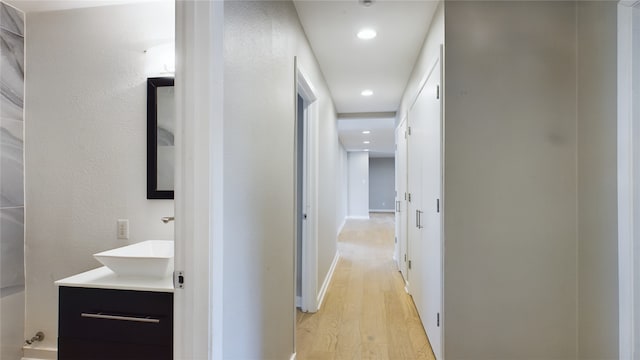 hallway with sink and light hardwood / wood-style floors