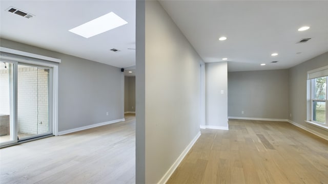 unfurnished room featuring light hardwood / wood-style floors and a skylight