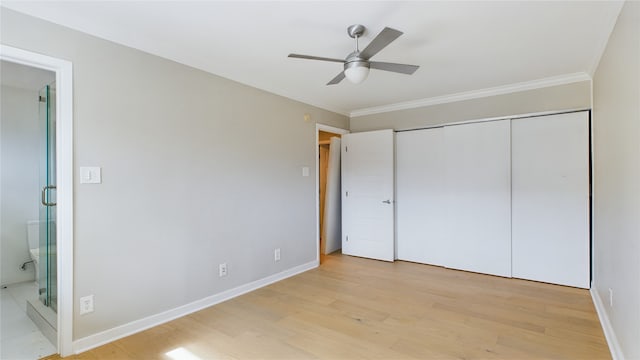 unfurnished bedroom featuring a closet, crown molding, ensuite bathroom, and light wood-type flooring