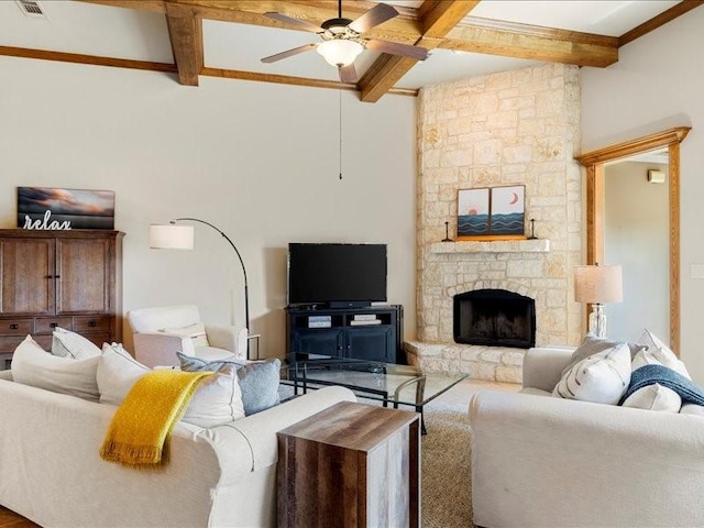 living room featuring beamed ceiling, a fireplace, and ceiling fan