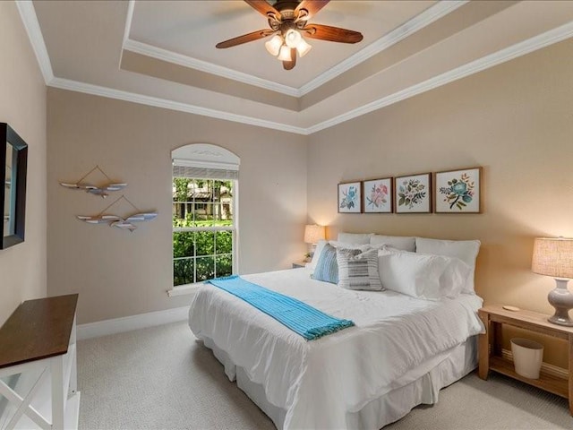 carpeted bedroom with ceiling fan, ornamental molding, and a raised ceiling