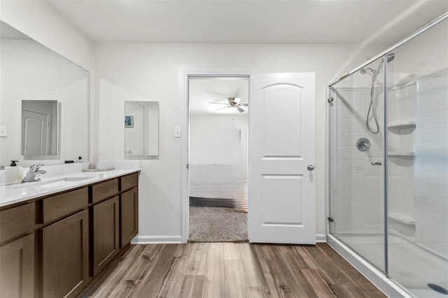 bathroom featuring ceiling fan, wood-type flooring, a shower with shower door, and vanity