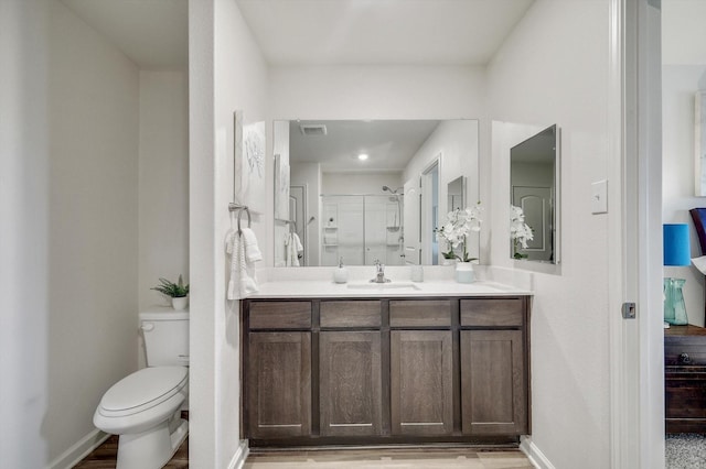 bathroom featuring vanity, toilet, a shower with shower door, and wood-type flooring