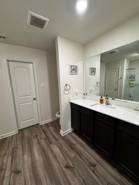 bathroom featuring walk in shower, wood-type flooring, toilet, and vanity