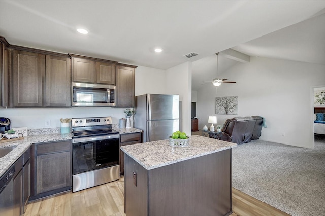 kitchen featuring stainless steel appliances, a kitchen island, dark brown cabinets, and vaulted ceiling with beams