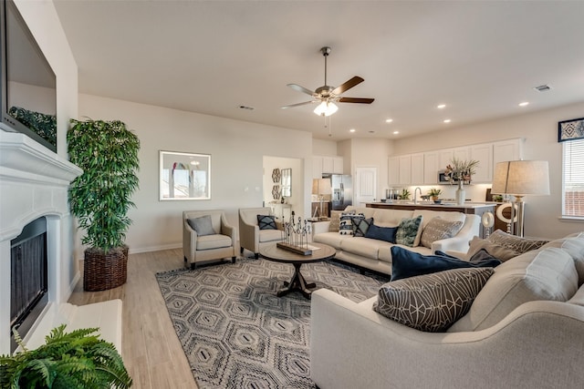 living room with light hardwood / wood-style floors and ceiling fan