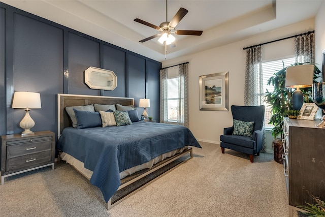 bedroom featuring a raised ceiling, carpet, and multiple windows