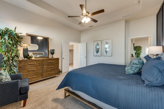 carpeted bedroom featuring a tray ceiling and ceiling fan