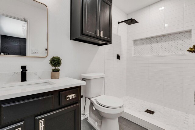 bathroom with vanity, a tile shower, and toilet