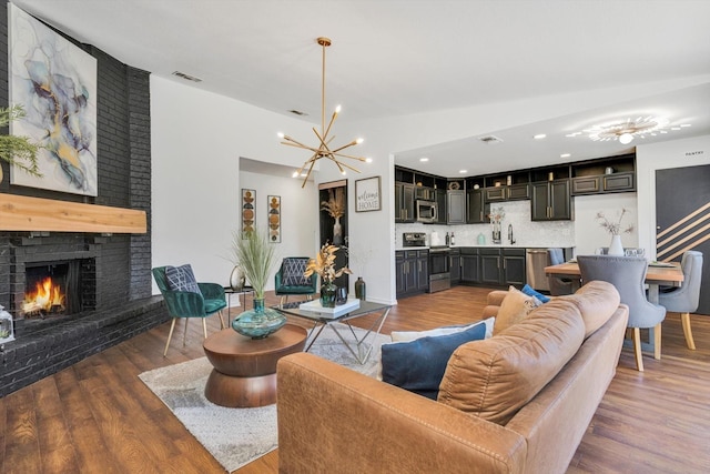 living room featuring a brick fireplace, sink, dark hardwood / wood-style floors, and a chandelier