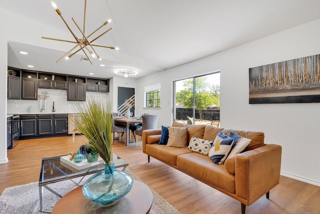 living room featuring sink, an inviting chandelier, and light hardwood / wood-style floors