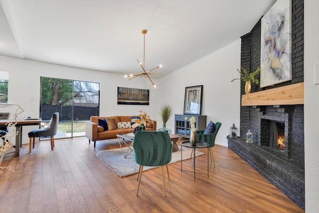 living room featuring wood-type flooring, vaulted ceiling, a brick fireplace, and plenty of natural light