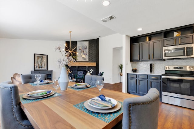 dining area featuring a notable chandelier, a fireplace, and dark hardwood / wood-style flooring