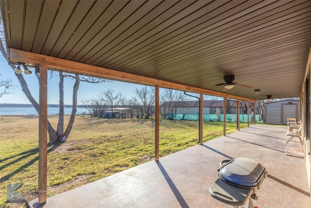 view of patio featuring a storage shed, ceiling fan, and a water view