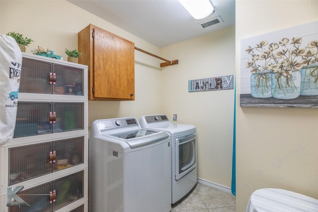 laundry area featuring light tile patterned floors, washing machine and dryer, and cabinets