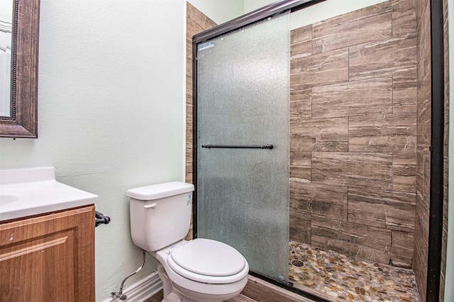 bathroom featuring vanity, a shower with shower door, and toilet