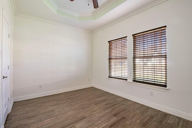 unfurnished room featuring a raised ceiling, ornamental molding, dark hardwood / wood-style floors, and ceiling fan