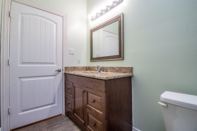 bathroom featuring wood-type flooring, toilet, and vanity