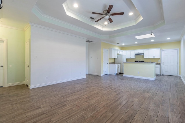 unfurnished living room with ceiling fan, wood-type flooring, a raised ceiling, and ornamental molding