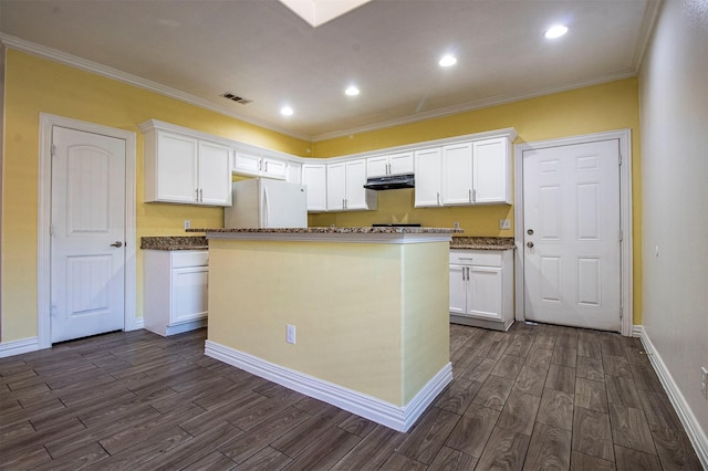 kitchen with white refrigerator, white cabinetry, and a kitchen island